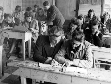 1945-1946 — Au premier plan, de gauche à droite, Jerzy Tomalak et Stanislaw Kubalski. Derrière eux, Jozefa Gigon. Le professeur est penché au-dessus de Janina Lamenta (Association Mémoire du lycée polonais).